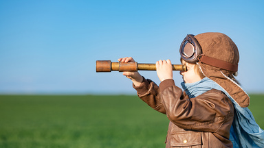 small child looking through telescope into the distance